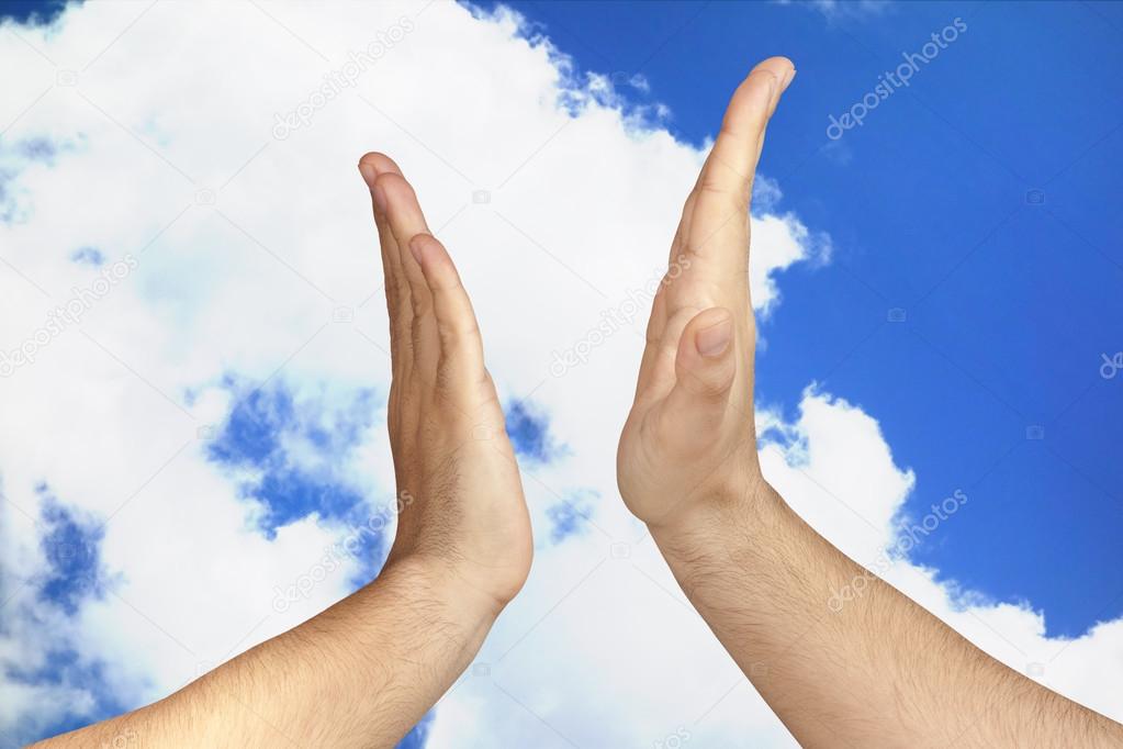 Hands giving a High Five outdoor against blue sky clouds