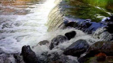 Nehirdeki şelale. Su taşların arasında gurulduyor.