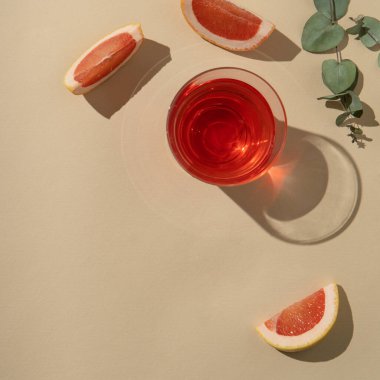 Greyfurt dilimleri ve yeşil okaliptüs yapraklı bir bardakta taze meyve suyu veya aperatif.