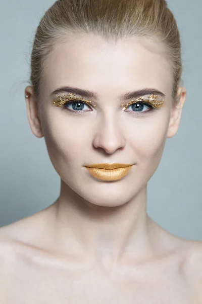 Closeup portrait of beautiful young woman with golden lips and golden foil on eyes — Stock Photo, Image