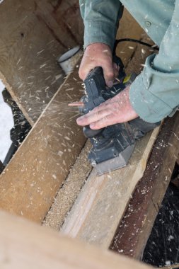 Erkekler bir elektrikli uçak ile ahşap bir tahta planya 