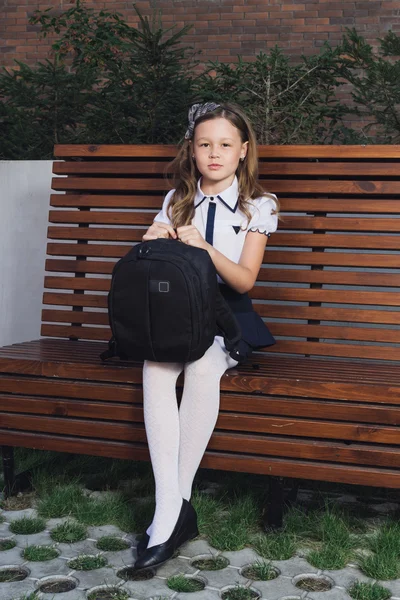 Écolière en uniforme attendant le bus pour l'école — Photo