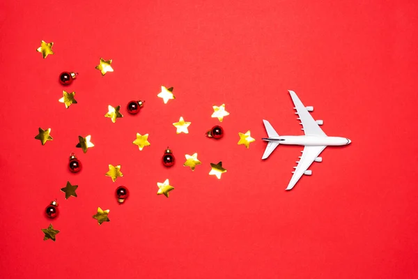 Uçak, süsler ve kırmızı kağıtta altın yıldızlı konfeti. Noel ya da yeni yıl festivali konsepti. Düz yerde, üst tarafta. Teslimat konsepti