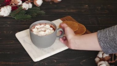 Bir kadın sıcak kakao içeceğiyle krem şanti karıştırıyor.