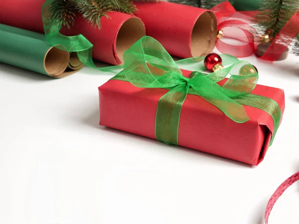 Gift boxes, red and green paper rolls and Christmas tree ornaments — Stock Photo, Image