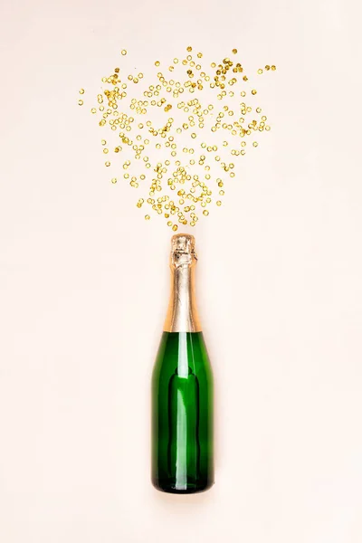 Garrafa verde de champanhe com salpicos de confetes dourados — Fotografia de Stock