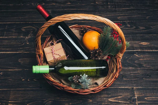 Piros és fehér borosüvegek karácsonyi ajándékkosárban — Stock Fotó