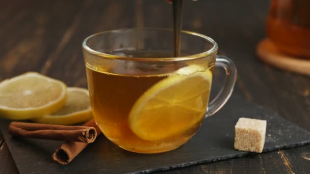 Glass cup of hot ginger tea with lemon on dark wooden table. — Stock Video