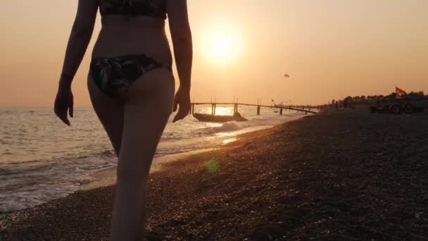 Женщина прогуливается по пляжу и оставляет следы на песке. — стоковое видео