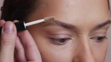 Makyaj sanatçısı kadın kaşlarına gölgeler sürer.