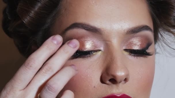 El maquillador aplica sombras de bronce en el ojo femenino — Vídeo de stock