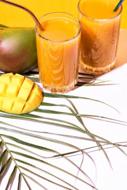 Bir bardak taze mango suyu kokteyli ve palmiye dalları.