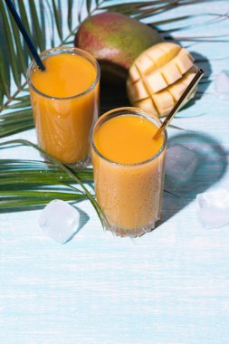 Bir bardak taze mango suyu kokteyli ve palmiye dalları.