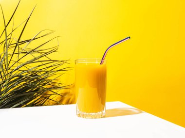 Bir bardak taze mango suyu kokteyli ve palmiye dalları.