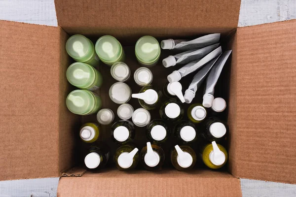 Cardboard box with cosmetic bottles on wooden background