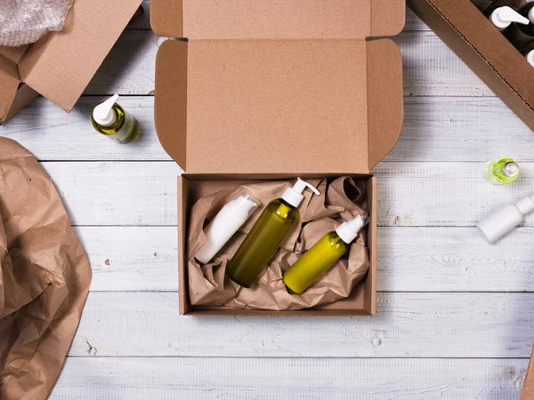 Cardboard box with cosmetic bottles on wooden background