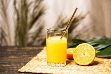Bir bardak taze portakal suyu hasır ve ahşap masa.