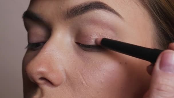 El maquillador aplica sombras de bronce en el ojo femenino — Vídeos de Stock