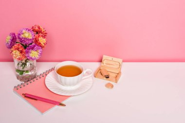 Beyaz masanın üzerinde bir fincan çiçekli çay olan ofis çalışma alanı.