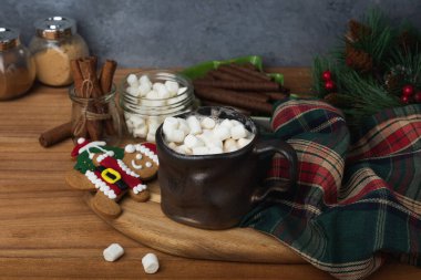 Noel Baba kurabiyesi, tarçın ve ahşap bir masa üzerindeki tarçın bezinin yanında mini bardakta çikolata içeceği..