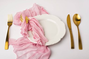 Merkezden biraz uzaklaştırılmış, şeffaf kumaşla sarılmış ve küçük altın botanik klipsleriyle vurgulanmış boş bir süsleme tablosu düzenleme