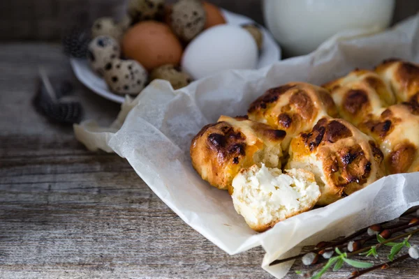 Bollos cruzados calientes de Pascua con huevos fondo de madera rústica —  Fotos de Stock