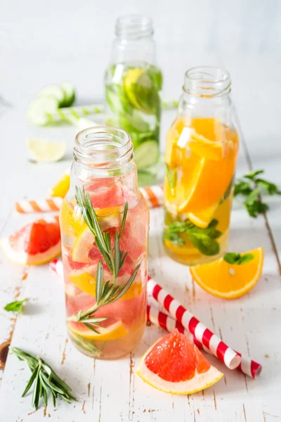 Selection of infused water in glass bottles, rustic wood background — Stock Photo, Image