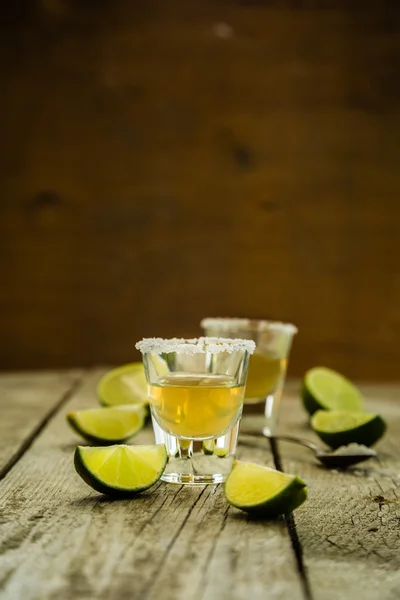 Tiros de tequila dorados sobre fondo de madera rústica —  Fotos de Stock