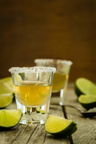 Gold tequila shots på rustika trä bakgrund — Stockfoto