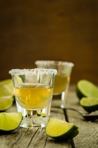 Gouden tequila shots op rustieke houten achtergrond — Stockfoto