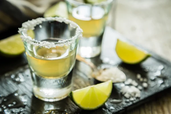 Tiros de tequila dorados sobre fondo de madera rústica —  Fotos de Stock