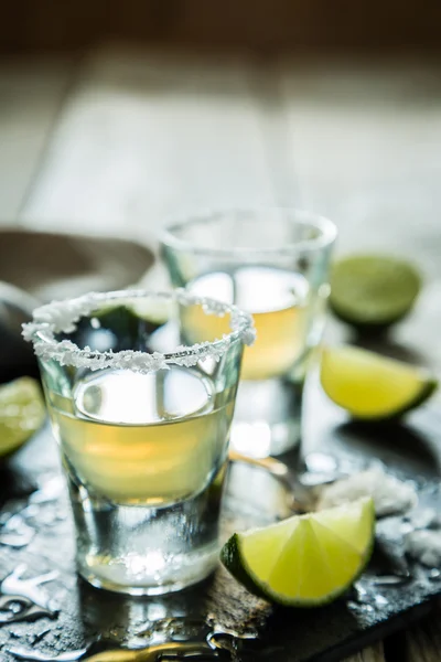 Gouden tequila shots op rustieke houten achtergrond — Stockfoto