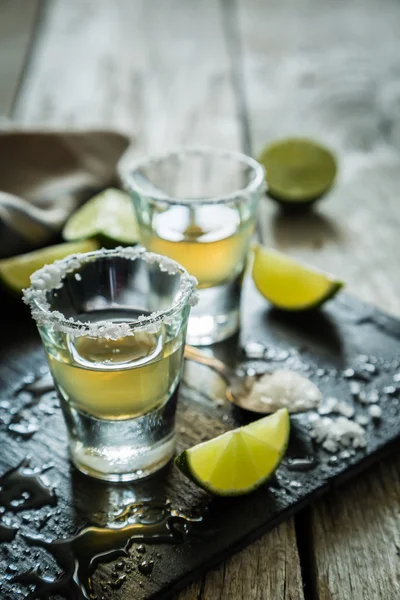 Gold tequila shots on rustic wood background — Stock Photo, Image