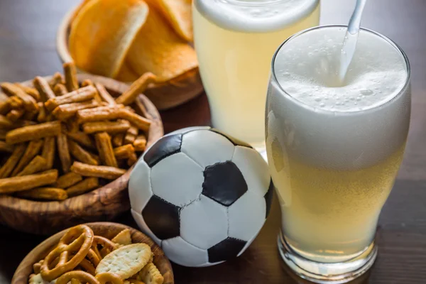 Bier gieten in glas met snacks en voetbal — Stockfoto