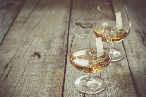 Cognac in glasses on rustic backgrpund — Stock Photo, Image