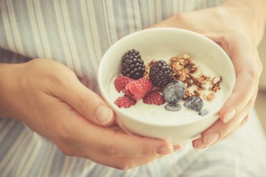 Kadın holding kase yoğurt glanola ve çilek ile