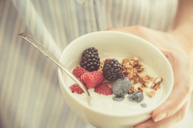 Kadın holding kase yoğurt glanola ve çilek ile