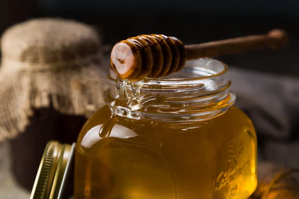 Miel de oro en frasco de vidrio con cazo — Foto de Stock