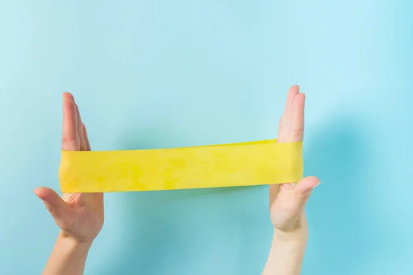 Home training concept - hands holding elastic bands on blue background — Φωτογραφία Αρχείου