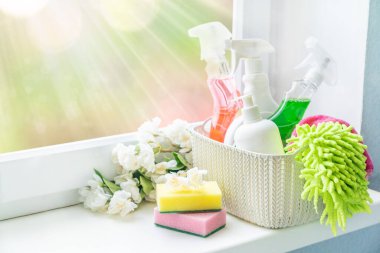 Spring cleaning concept - cleaning supplies and flowers on blur background clipart