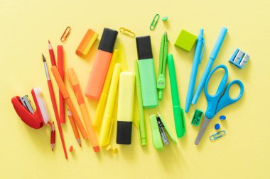 Okul konseptine geri dönelim. Parlak sarı arka planda renkli okul malzemeleri.