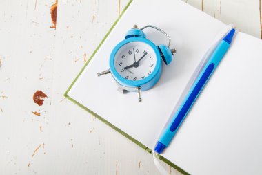 Üstünde defter kalem ile saat