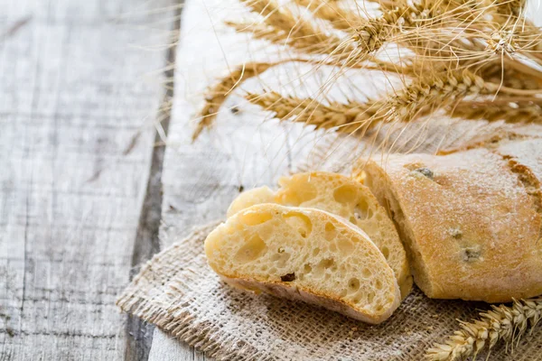 Ciabatta e trigo sobre fundo de madeira — Fotografia de Stock