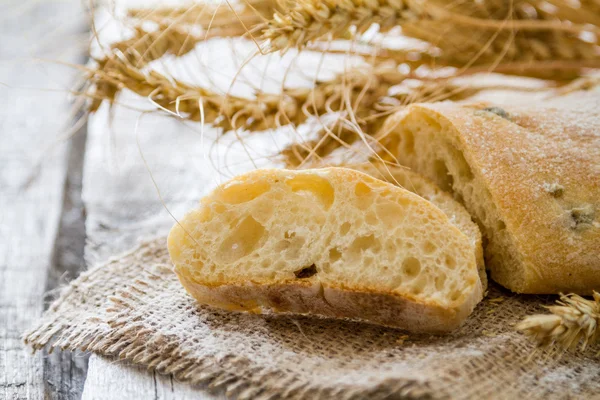 Ciabatta e trigo sobre fundo de madeira — Fotografia de Stock