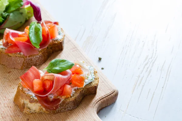 Bruschetta de tomate con hojas de albahaca —  Fotos de Stock