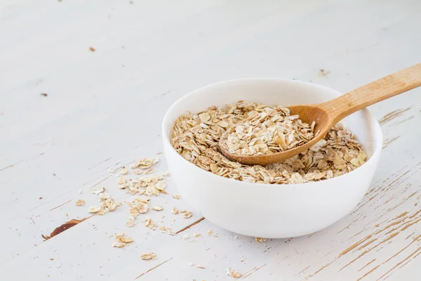 Avena en tazón blanco con cuchara de madera — Foto de Stock