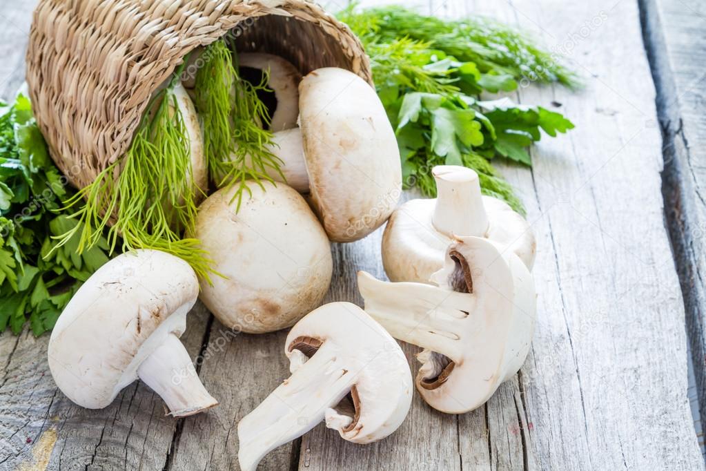 Mushrooms and herbs in basket, rustic wood background