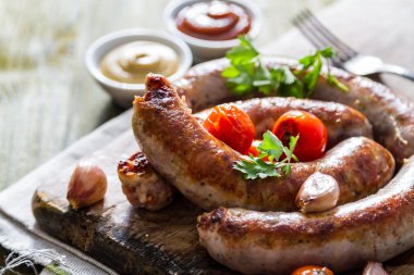 Grilled sausages served on wood board clipart