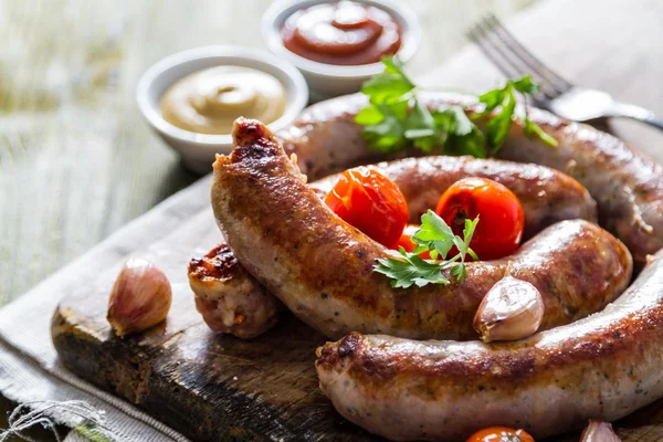 Grilled sausages served on wood board — Stock Photo, Image