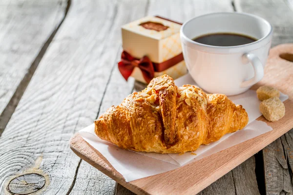 Läckra färska croissanter med kaffe och nuvarande — Stockfoto